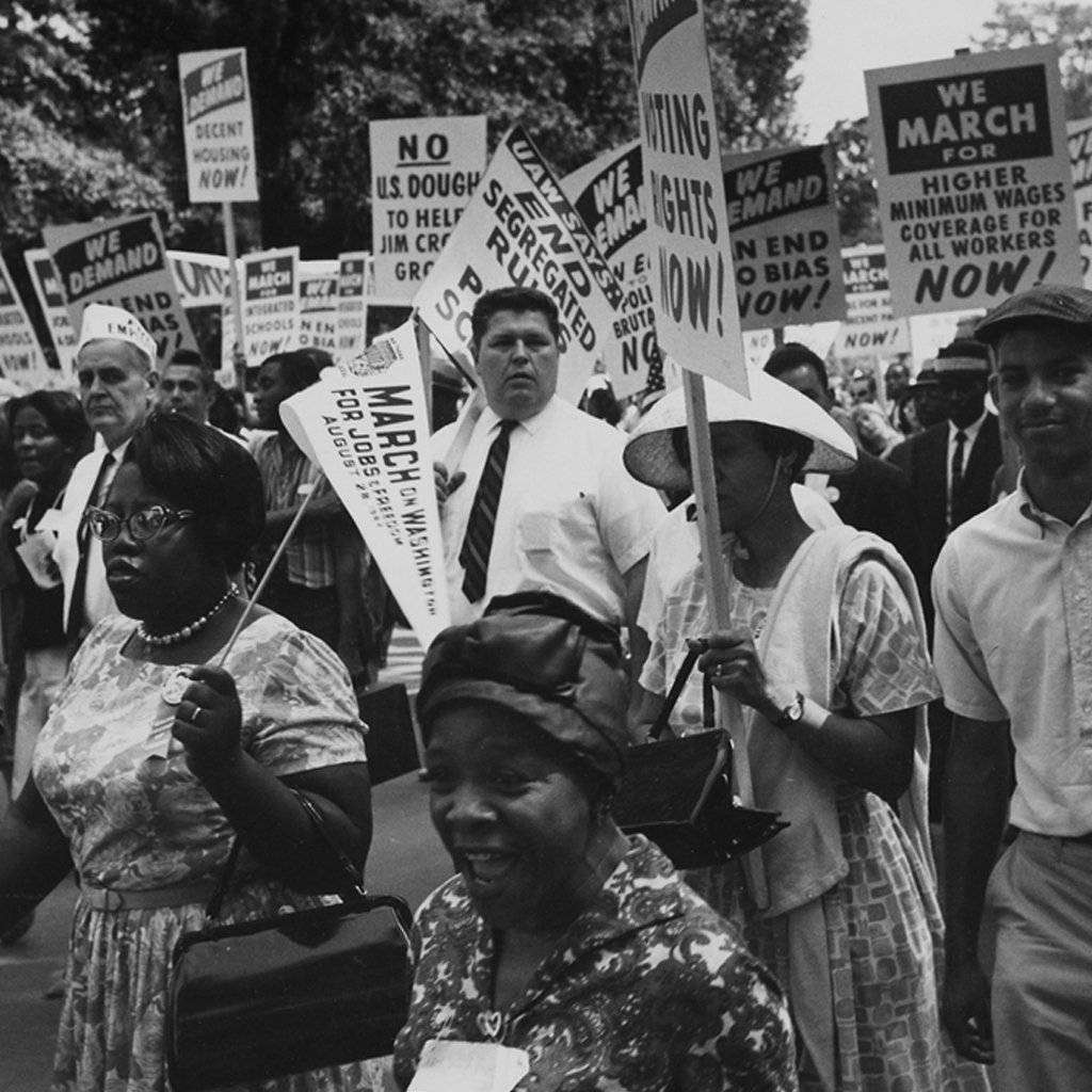 Protestors carrying signs saying 'We march for effective civil rights laws now'