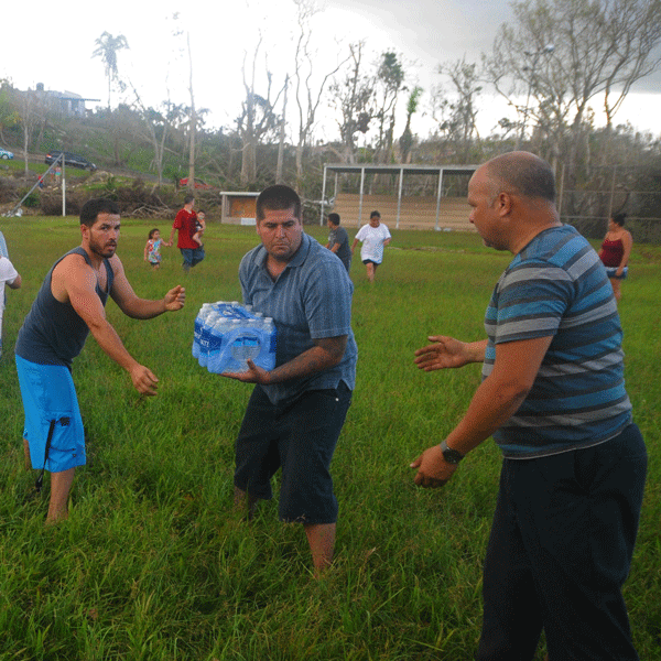 Men standing in a line passing a case of water bottles