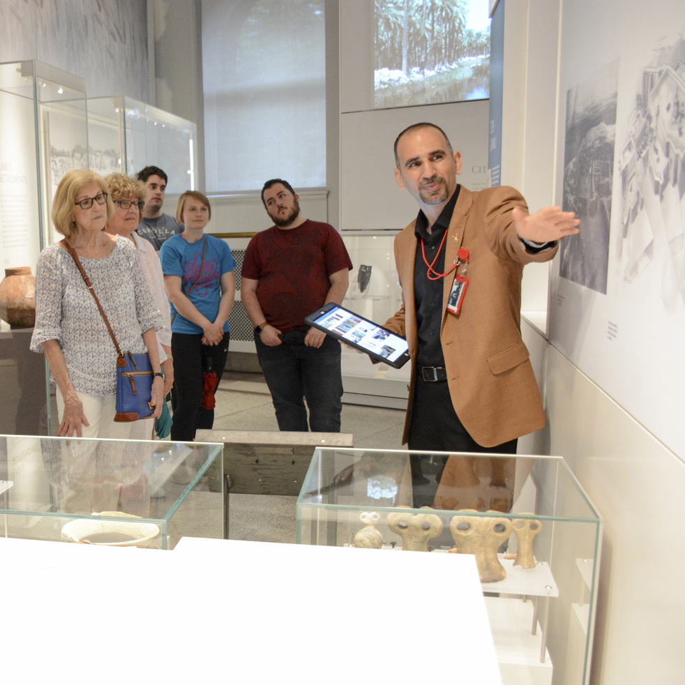 People listening to a tour guide explain a photo at a museum