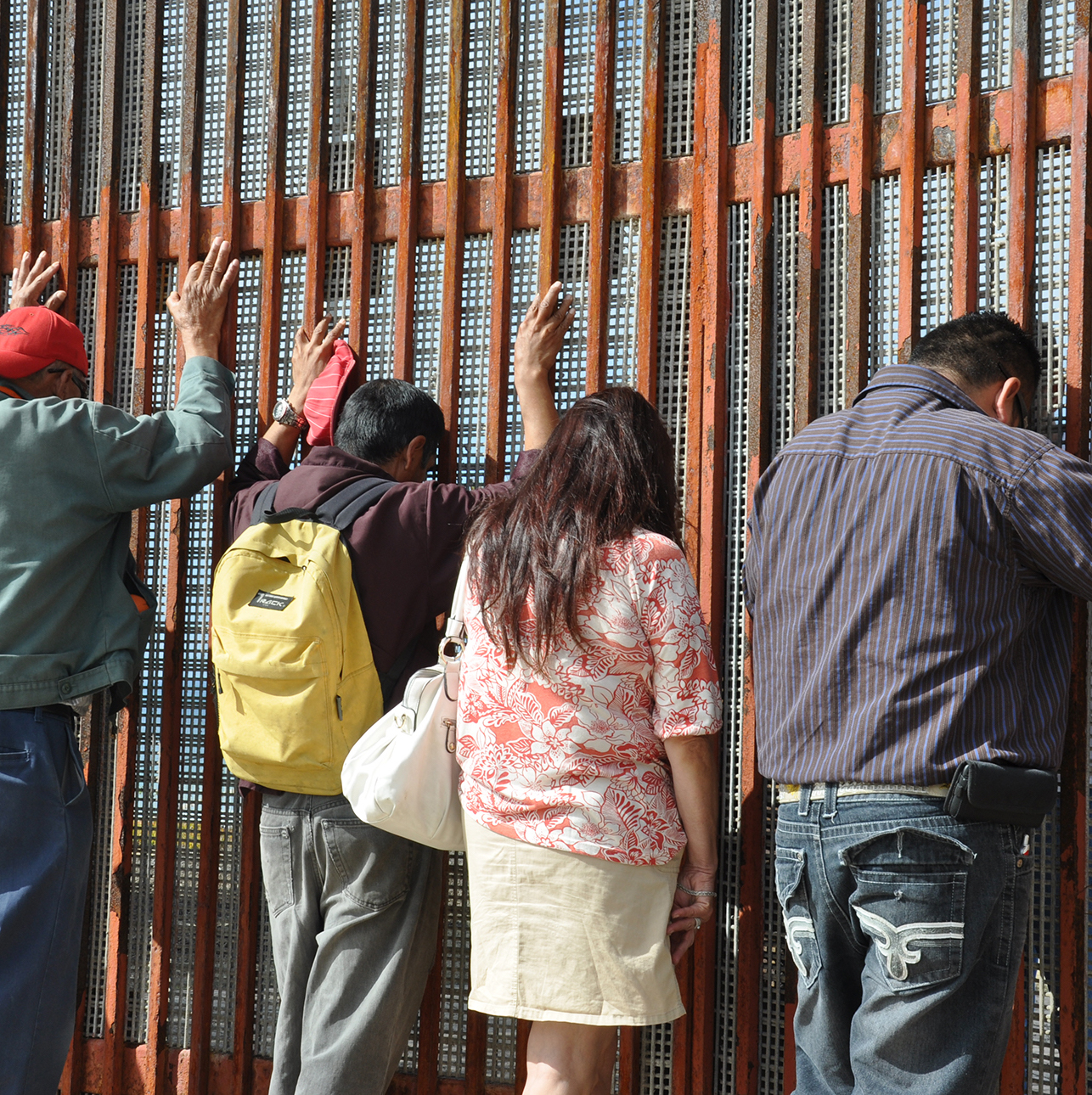 Family standing against a metal wall with their heads down and arms up