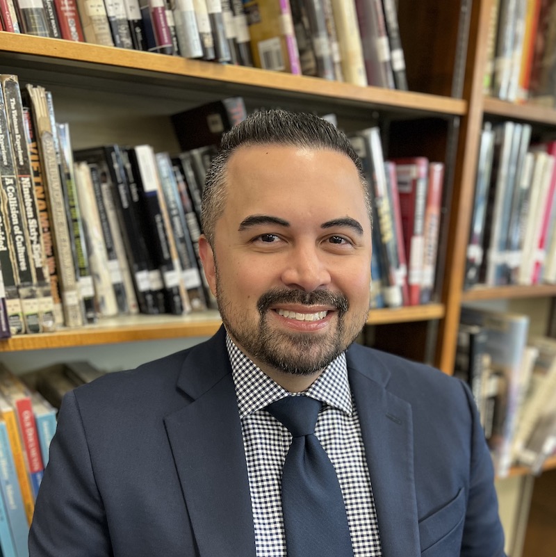 Justin Aromin in front of bookshelves